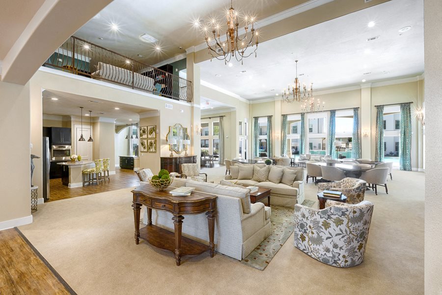 a lobby with a chandelier and sitting areas at a senior apartment community